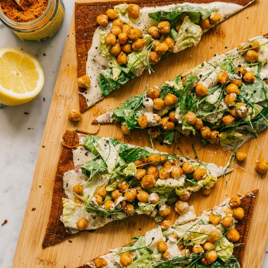 In Dreiecke geschnittener Pizzaboden belegt mit Kicherebsen und Spicy Ceasar Salat